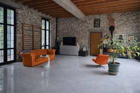 Séjour du manoir : murs en pierre, charpente apparente et mobilier en cuir
